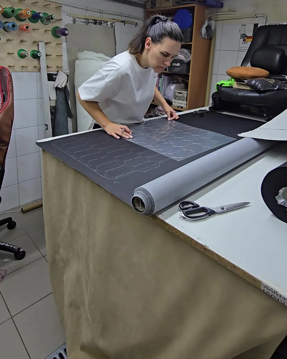 Oksana przygotowuje materiał i wzory przy stole roboczym w pracowni CarStitch.
